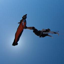 Video | Parachutespringer surft op rug van wingsuitvlieger